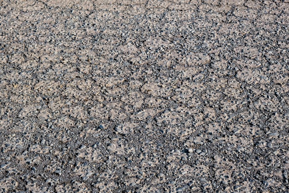 Pracownik budowlany precyzyjnie aplikuje gorącą masę bitumiczną na uszkodzony fragment parkingu